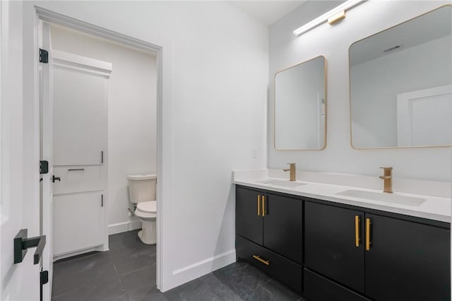 bathroom with toilet, vanity, and tile patterned flooring