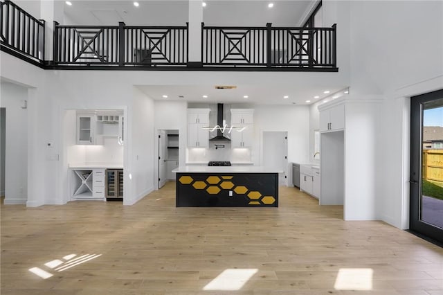 living room featuring light hardwood / wood-style floors, a high ceiling, and wine cooler