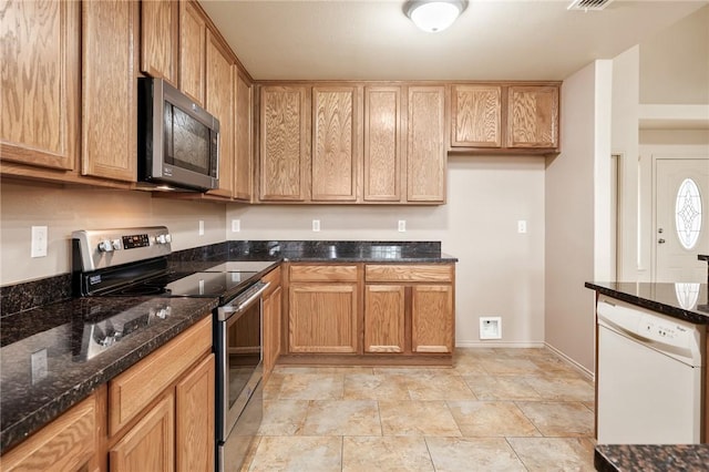 kitchen featuring stainless steel appliances and dark stone countertops