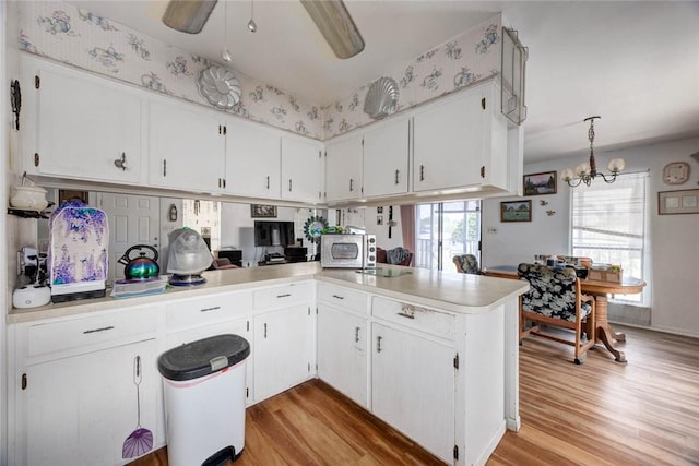 3410 Laguna Shrs, Corpus Christi, TX 78418 - kitchen with light wood-style floors, light countertops, white cabinetry, and a chandelier