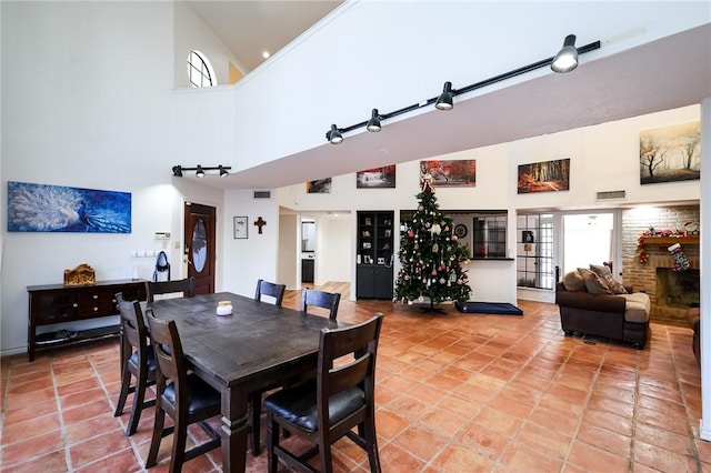 tiled dining room featuring a high ceiling and a brick fireplace