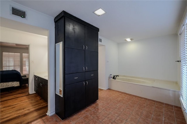 bathroom with tile patterned floors, a washtub, and vanity