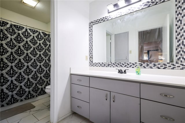 bathroom featuring vanity, toilet, and tasteful backsplash