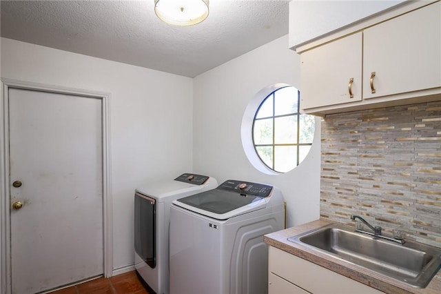 laundry area featuring cabinets, a textured ceiling, sink, dark tile patterned flooring, and washing machine and clothes dryer