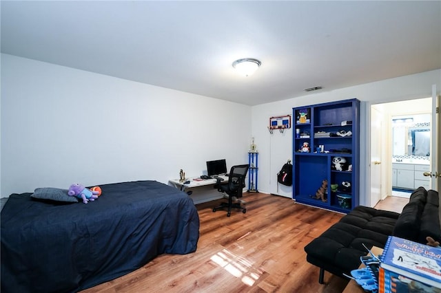 bedroom with ensuite bath and hardwood / wood-style flooring