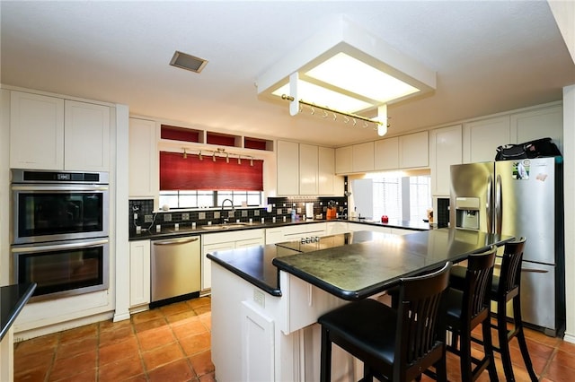 kitchen featuring white cabinets, sink, a kitchen bar, and stainless steel appliances