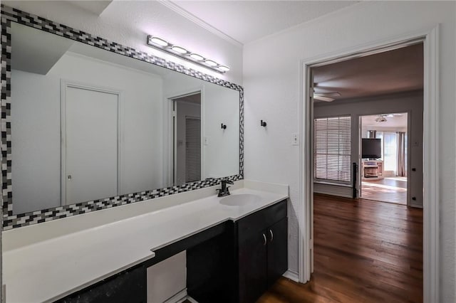 bathroom featuring wood-type flooring, vanity, ceiling fan, and ornamental molding