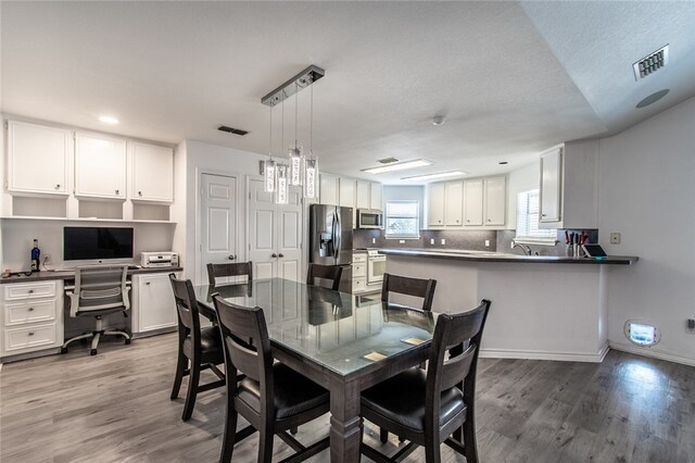 dining area featuring hardwood / wood-style floors, built in desk, a textured ceiling, and sink