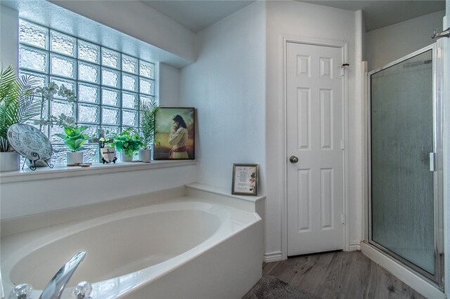 bathroom with shower with separate bathtub and wood-type flooring