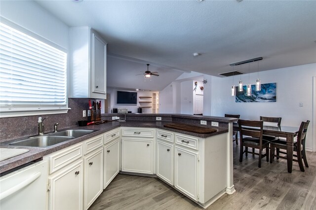 kitchen with dishwasher, kitchen peninsula, sink, and white cabinets