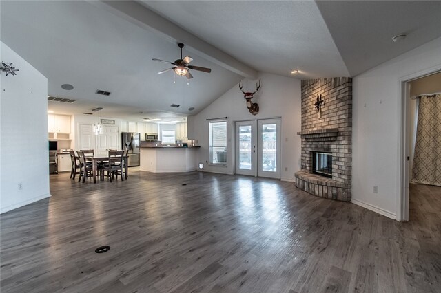 unfurnished living room with a brick fireplace, vaulted ceiling with beams, dark wood-type flooring, and ceiling fan