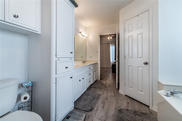 bathroom with ceiling fan, hardwood / wood-style floors, vanity, a bathing tub, and toilet