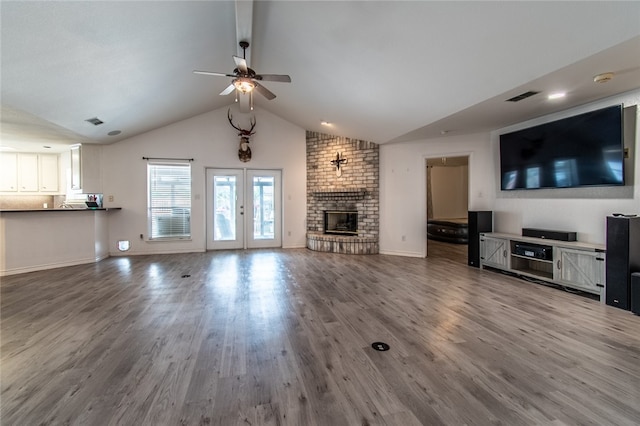 unfurnished living room featuring a fireplace, lofted ceiling, ceiling fan, and wood-type flooring