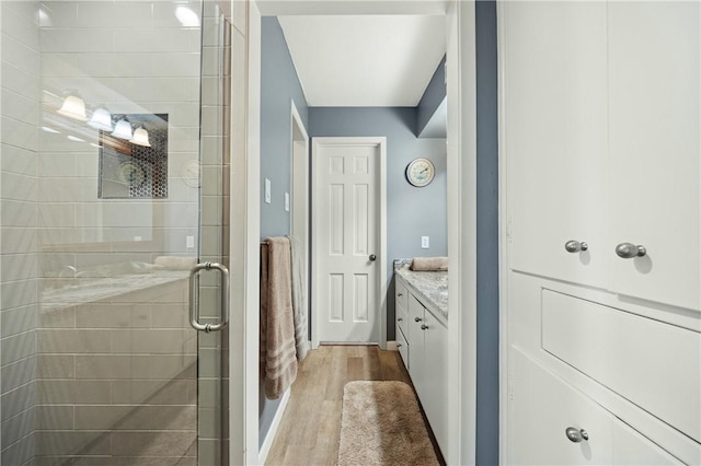 bathroom with walk in shower, vanity, and wood-type flooring