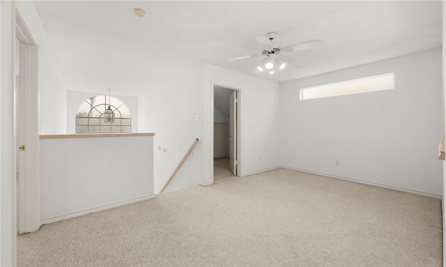 empty room with light colored carpet and ceiling fan with notable chandelier