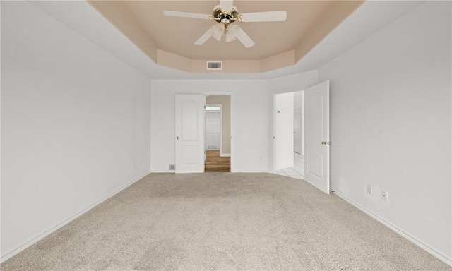 unfurnished room featuring light carpet, ceiling fan, and a tray ceiling