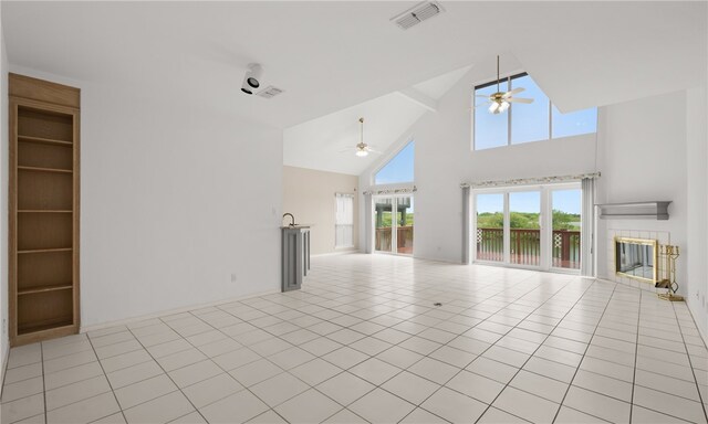 unfurnished living room featuring high vaulted ceiling, ceiling fan, a tile fireplace, and light tile patterned floors