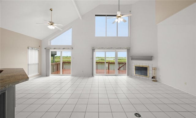 unfurnished living room featuring high vaulted ceiling, beam ceiling, ceiling fan, and a tile fireplace