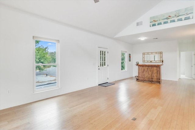unfurnished living room with light wood-style floors, high vaulted ceiling, visible vents, and a healthy amount of sunlight