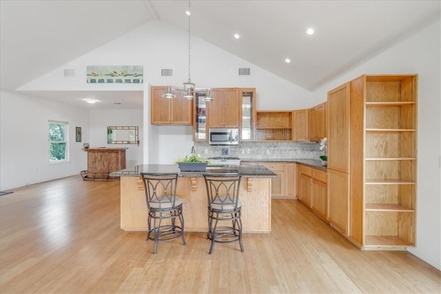 kitchen with a kitchen island, dark countertops, open shelves, high vaulted ceiling, and stainless steel microwave