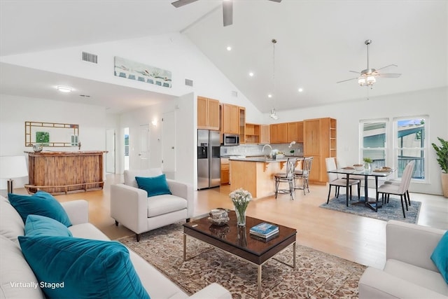 living area featuring visible vents, ceiling fan, high vaulted ceiling, and light wood-type flooring