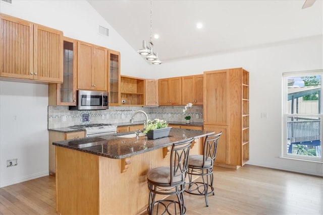kitchen with white gas range, visible vents, open shelves, light wood-type flooring, and stainless steel microwave