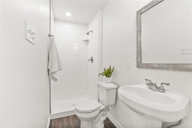 full bathroom featuring a stall shower, a sink, toilet, and wood finished floors