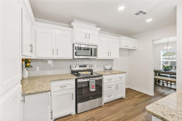 kitchen with light stone counters, decorative light fixtures, and white cabinetry