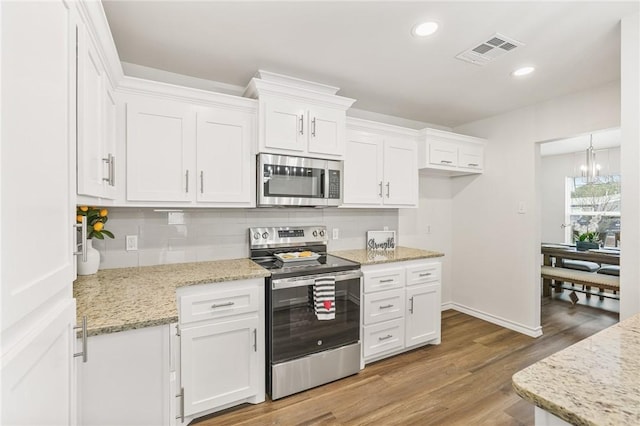 kitchen featuring stainless steel appliances, tasteful backsplash, visible vents, white cabinetry, and wood finished floors