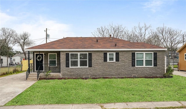 view of front of home featuring stone siding, a front lawn, and roof with shingles