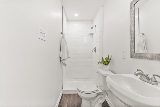 full bath with a stall shower, a sink, toilet, and wood finished floors