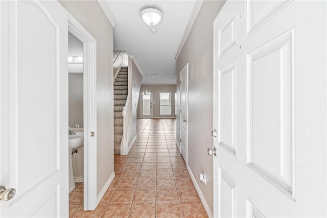 corridor with stairs, crown molding, light tile patterned flooring, and baseboards