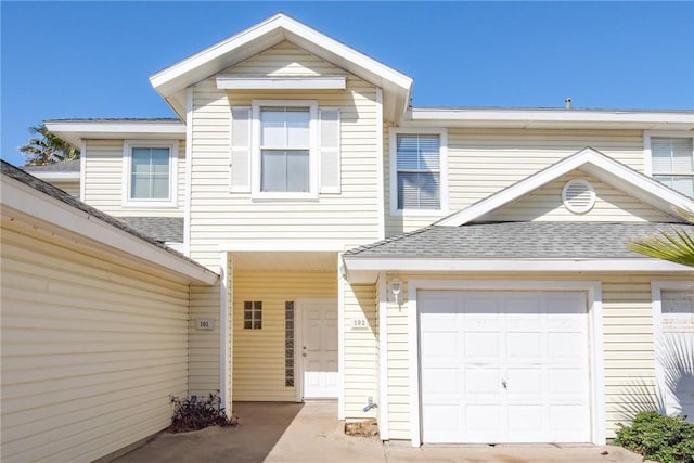 view of property with an attached garage and roof with shingles