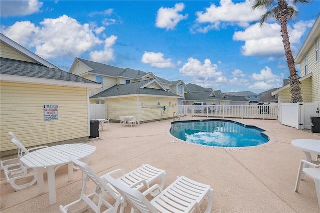 community pool with a fenced backyard, a residential view, and a patio