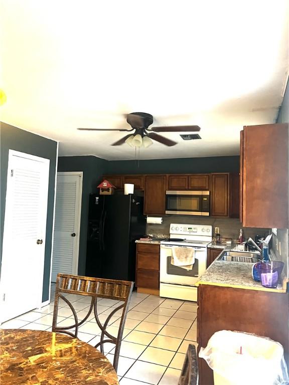 kitchen featuring electric stove, sink, ceiling fan, light tile patterned flooring, and black fridge with ice dispenser