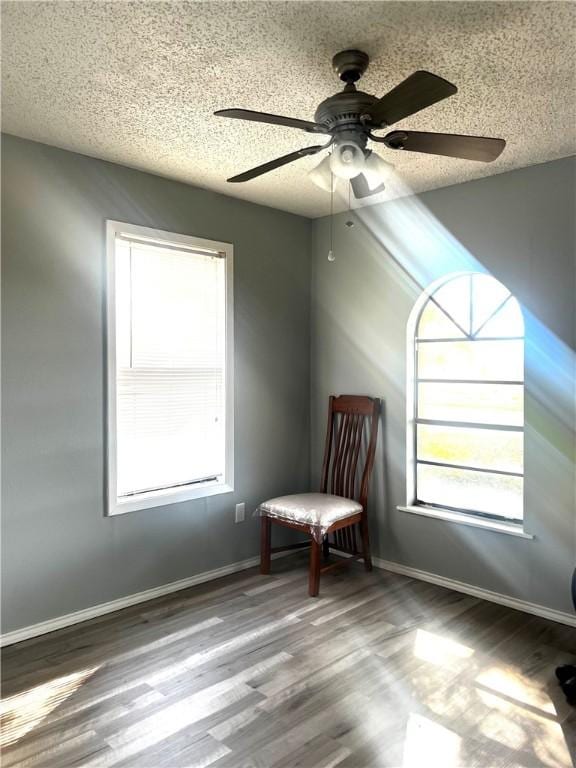 unfurnished room with hardwood / wood-style flooring, ceiling fan, and a textured ceiling