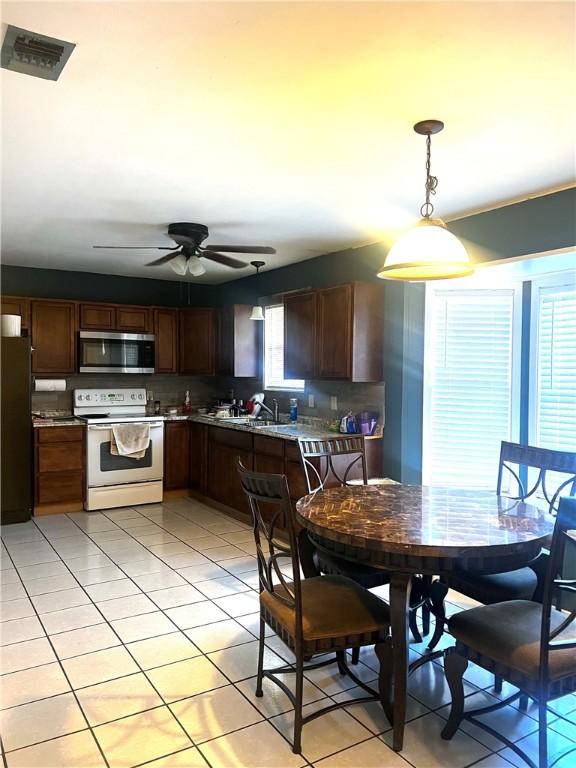 kitchen featuring refrigerator, ceiling fan, light tile patterned floors, white range with electric cooktop, and hanging light fixtures