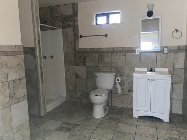 bathroom featuring vanity, a healthy amount of sunlight, and a tile shower