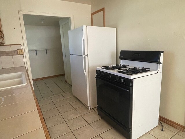 kitchen with white appliances, sink, and light tile patterned flooring