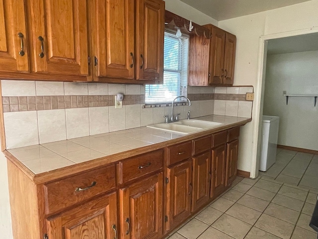 kitchen with washer / dryer, backsplash, light tile patterned floors, sink, and tile counters