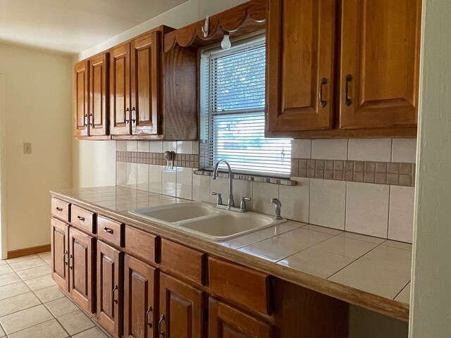 kitchen with tile countertops, sink, decorative backsplash, and light tile patterned floors