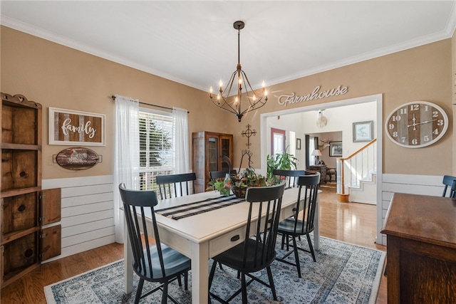 dining area with hardwood / wood-style floors, an inviting chandelier, and ornamental molding