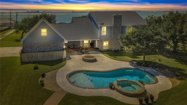 pool at dusk featuring a lawn, a patio area, an in ground hot tub, and an outdoor fire pit