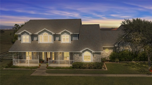 cape cod-style house featuring a lawn and covered porch