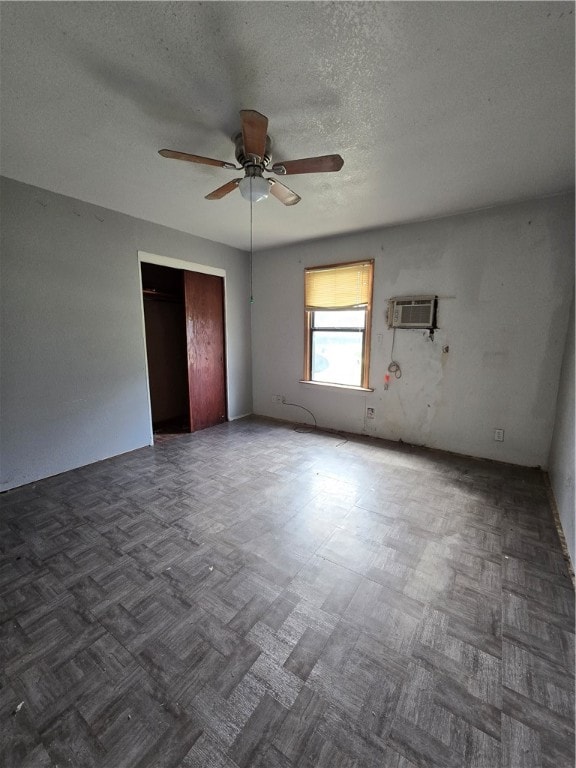 unfurnished room with a textured ceiling, an AC wall unit, and ceiling fan