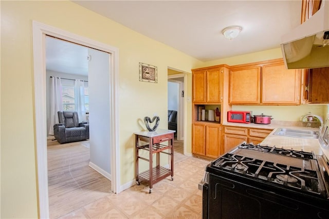 1001 Azalea Dr, Corpus Christi, TX 78408 - kitchen featuring under cabinet range hood, gas stove, a sink, light countertops, and baseboards