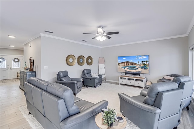 living room featuring ornamental molding, light hardwood / wood-style floors, and ceiling fan