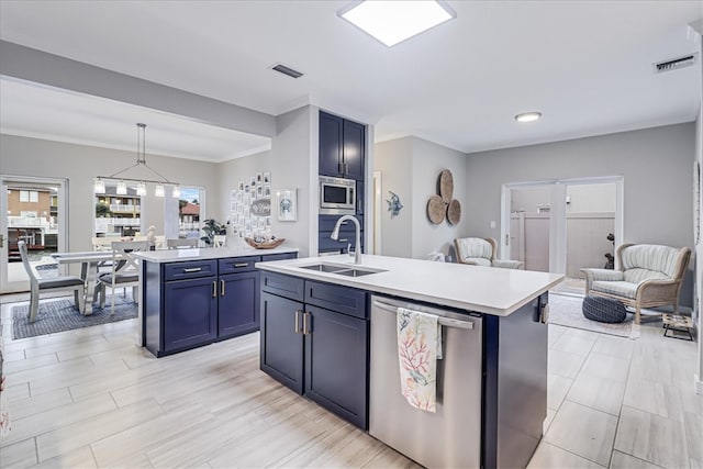 kitchen featuring hanging light fixtures, blue cabinetry, a kitchen island with sink, and appliances with stainless steel finishes