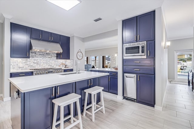 kitchen featuring a kitchen breakfast bar, appliances with stainless steel finishes, blue cabinets, and plenty of natural light