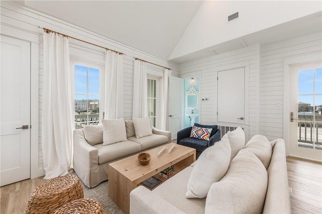 living room featuring high vaulted ceiling and light hardwood / wood-style floors